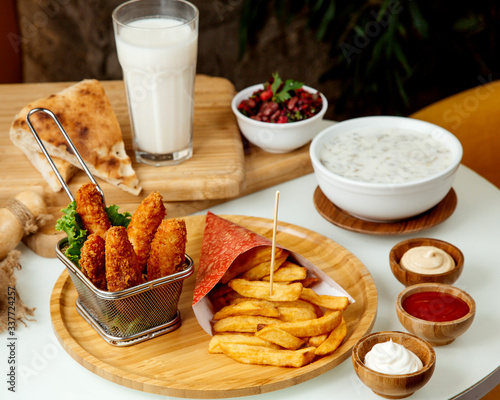 french fries and chicken nuggets in batter on a wooden board