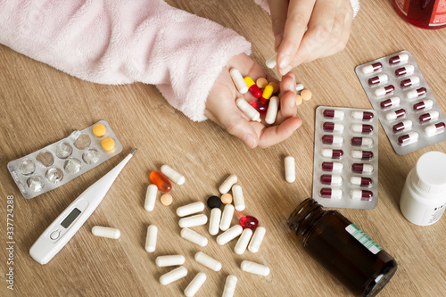 Children's hands with medicines on a wooden table. A small child left unattended plays dangerous drugs.