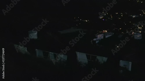 AERIAL: Spectacular Flight Close over Hollywood Sign Letter at Night with Los Angeles Cityscape Lights 