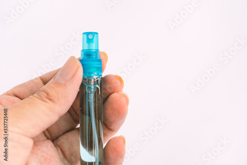 Isolated on white background  Close up small bottle Alcohol in hand. Slim glass spray bottle with alcohol  small size container for daily carry. Light blue water  blue spray cap.