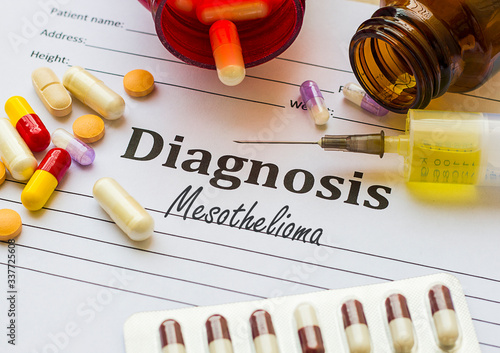 Mesothelioma  - Diagnosis written on a piece of white paper with medication injection, syringe and pills