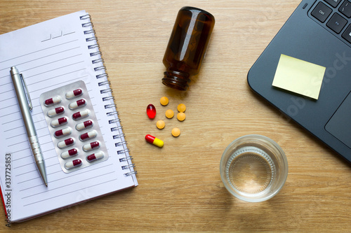 On-line treatment concept with bottles of medicine pills on the wooden table