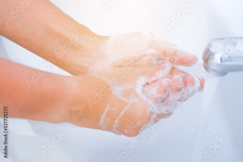 Close-up of young women washing hands with soap rubbing fingers and skin under faucet water flows on white basin for pandemic prevention Corona virus, Covid-19