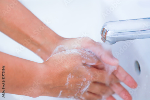 washing hands with soap rubbing fingers and skin under faucet water flows