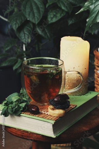Obraz na płótnie Dark mystic and calm mood. Book and hot tea with mint and honey on table with green plant w salonie