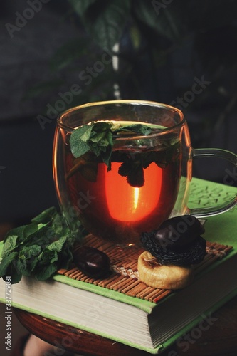 Obraz na płótnie Dark mystic and calm mood. Book and hot tea with mint and honey on table with green plant w salonie