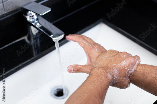 Man is washing his hands in a sink sanitizing the colona virus for sanitation and reducing the spread of COVID-19 spreading throughout the world  Hygiene  Sanitation concept.