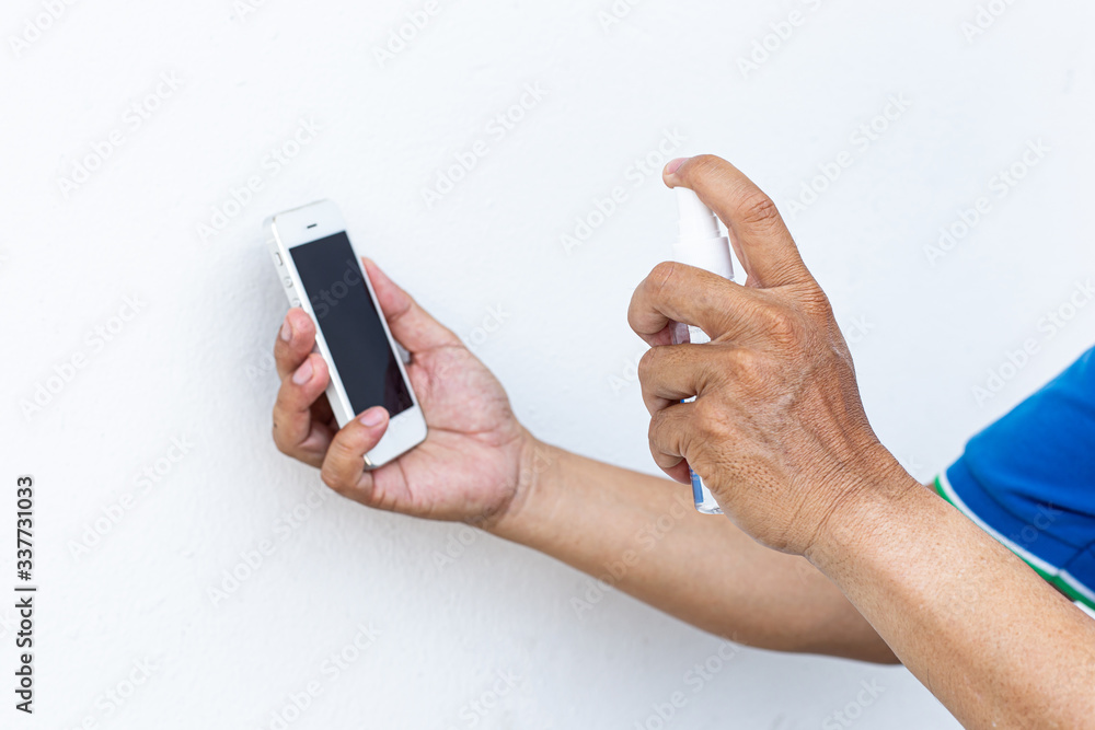 Men use alcohol spray to get rid of bacteria and viruses on mobile phones, Inhibition and prevention of Covid-19 virus infection using 70 percent alcohol, protect virus concept. Men use alcohol spray to get rid of bacteria and viruses on mobile phones, Inhibition and prevention of Covid-19 virus infection using 70 percent alcohol, protect virus concept.
