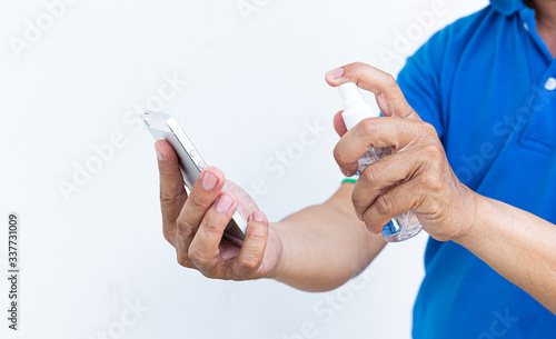 Men use alcohol spray to get rid of bacteria and viruses on mobile phones, Inhibition and prevention of Covid-19 virus infection using 70 percent alcohol, protect virus concept.