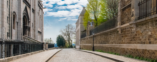 Fotografia Paris, Montmartre, typical paved street, with the Sacre-Coeur basilica on the le