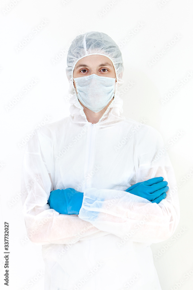 A man in a protective suit and face mask looks at the camera with his arms folded. Isolated on a white background. A man in a protective suit and face mask looks at the camera with his arms folded. Isolated on a white background.