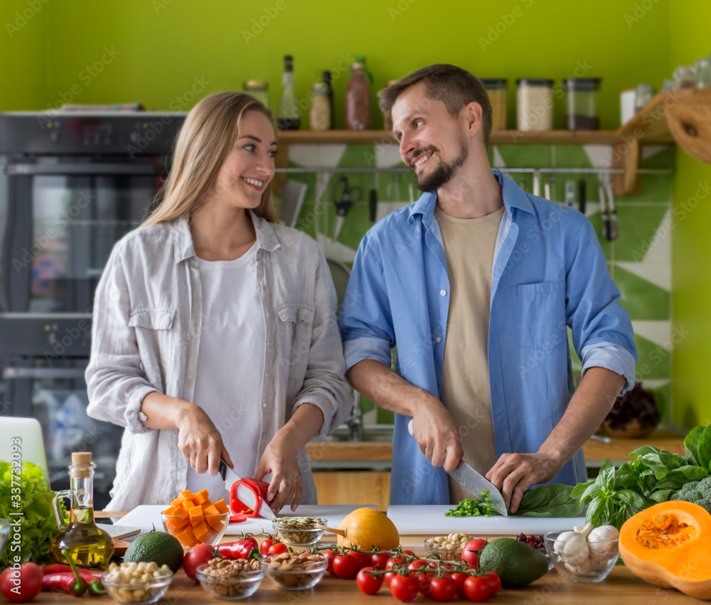 Attractive young couple cooking vegetable salad together in kitchen Attractive young couple cooking vegetable salad together in kitchen