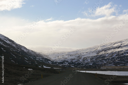 Dark asphalt road on the background of mountains and ocean. The tour around Iceland. Geothermal heat this way