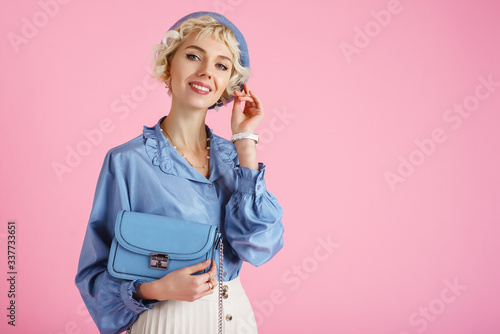Papier peint Fashion portrait of elegant happy smiling lady wearing trendy spring outfit: blue blouse, beret, holding small stylish faux leather bag, posing on pink background