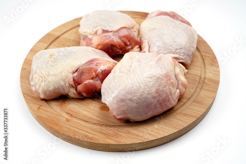Fresh chicken thighs on a chopping Board. Isolate on a light background