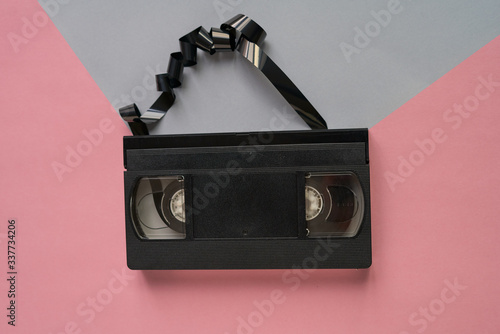 Top of view A videotape unraveled on a pink and grey background.