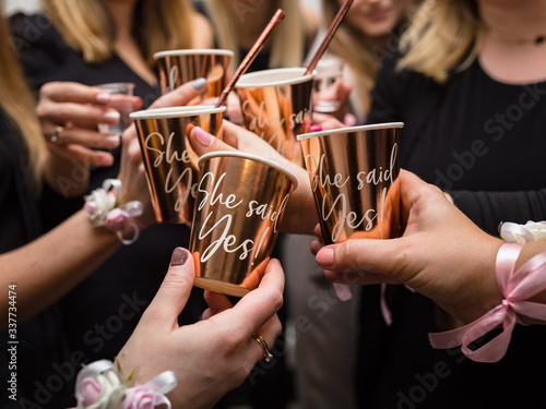 Hands of the bride and bridesmaids holding cups at a bachelorette party - raising a toast photo