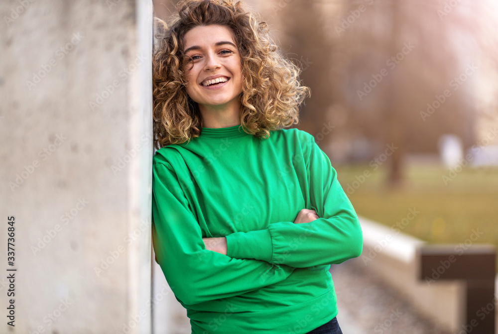 Obraz premium Portrait of young woman with curly hair in the city 