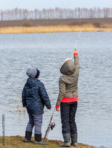 Mom and son are fishing in the lake for fishing rod.