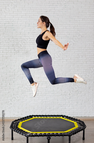 Relaxed woman jumping on trampoline.young fitness girl trains on a mini trampoline in the Studio
