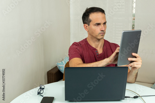 44 year old man doing home office with computer and tablet (photo 2). photo