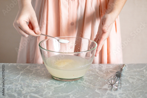 A woman pours sugar into a bowl, the process of kneading the dough.
