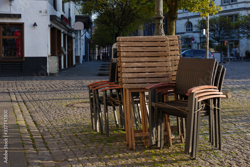 Selected focus at stack of outdoor chairs of pub, cafe and restaurant shutdown during quarantine from contagion of COVID-19 on walking street in old town. © Peeradontax