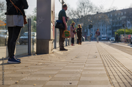 Low angle and selected focus view of people stand and wait with social distancing for TRAM, public transportation, during quarantine from contagion of COVID-19 in Düsseldorf, Germany.