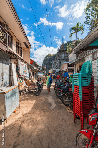 A young tourist man takes a walk in a narrow street near a cliff in the El Nido city, Palawan, Philippines
