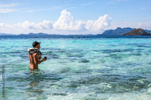 A young tourist man walking inside the water in Coron, Philippines