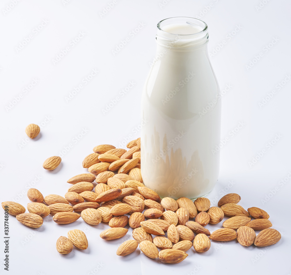 almonds and a bottle of almond milk on a white background. Vegan milk. almonds and a bottle of almond milk on a white background. Vegan milk.