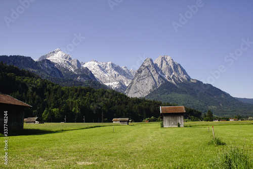 Deutsche Alpengipfel in der Nähe von Garmisch-Patenkirchen mit Wiese, Wald und Hütten.