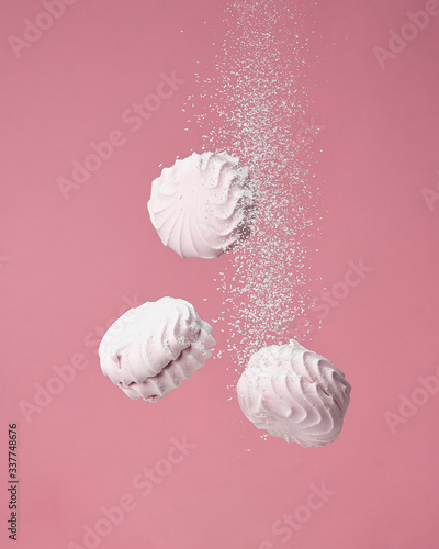  Soaring pink zephyr marshmallow on pink background. flying food levitation, sweet candy dessert.