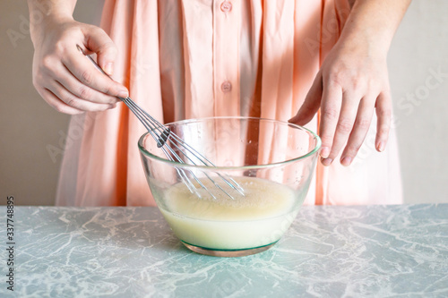 A woman mixes ingredients with a whisk, the process of kneading the dough.