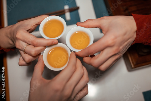 a group of people drinks Chinese green tea from pial in a Chinese restaurant. top view, close-up on hands