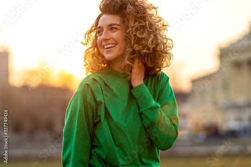 Fotografi Portrait of young woman with curly hair in the city