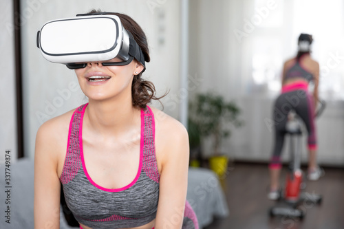 Young girl stay home in quarantine and go in for sports with virtual reality glasses. Woman exercise yoga while at home wearing virtual reality glasses