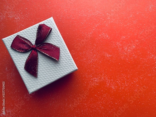 white gift box with red bow on a red background. photo