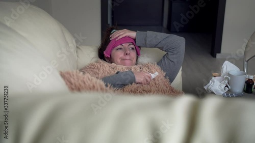 sad woman is sick alone at home is lying on the couch, cough, fever, depression photo