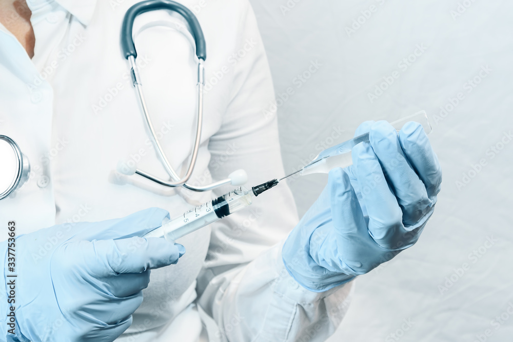A medical syringe with a vaccine in the hands of a doctor, closeup. A medical syringe with a vaccine in the hands of a doctor, closeup.
