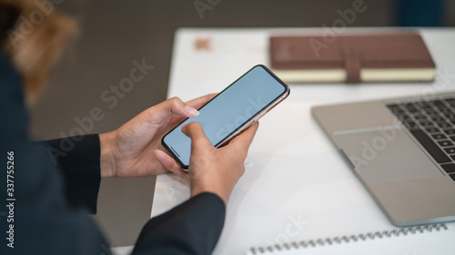 Woman sitting and holding blank screen mock up mobile phone 
