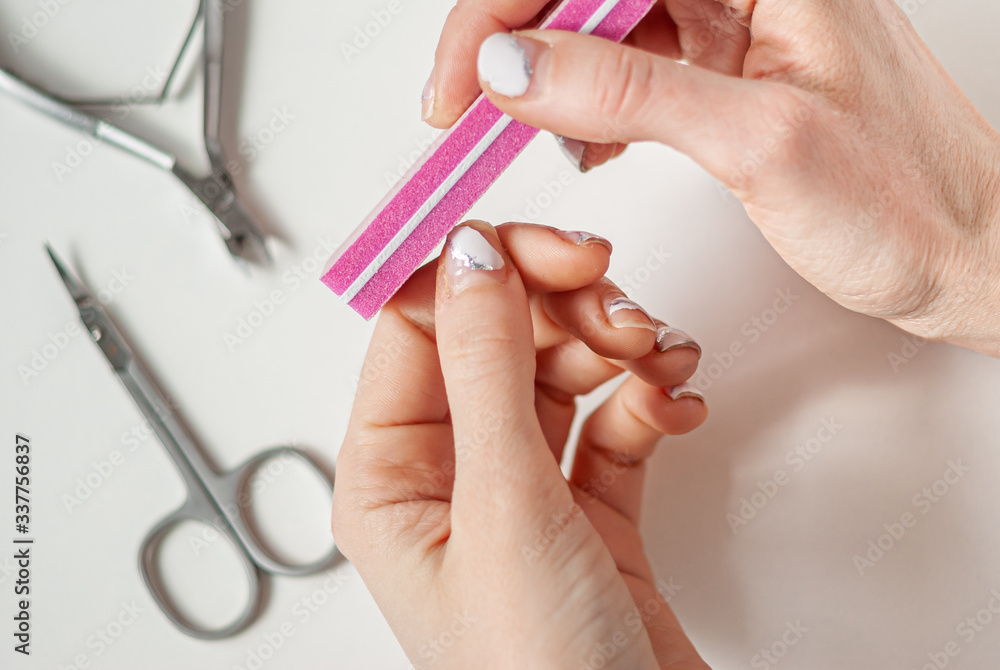 Quarantined girl with old manicure and a nail file. We do manicure ourselves, stay at home. Peeling, shabby gel polish Quarantined girl with old manicure and a nail file. We do manicure ourselves, stay at home. Peeling, shabby gel polish
