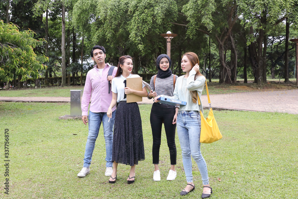 Fototapeta premium Young asian malay chinese man woman outdoor park walk stand study talk discuss point laptop file book backpack