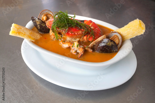 Peruvian seafood: Parihuela or special seafood soup with crab, mussels and cassava, decorated with seaweed and served on a white bowl photo