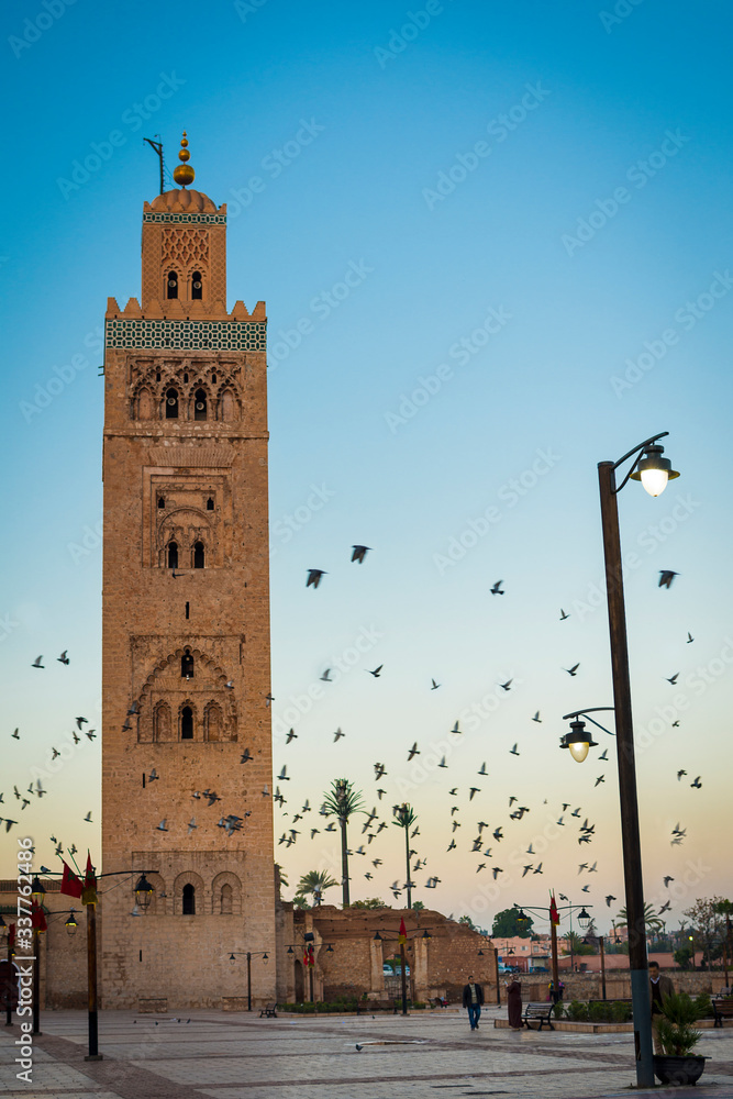 koutubia tower in marrakech at sunrise with birds flying