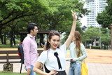 Young asian malay chinese man woman outdoor park walk stand study talk discuss point laptop file book backpack female look forward ok finger sign