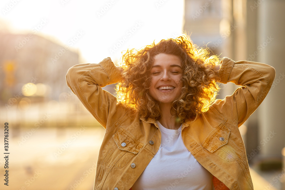 © pikselstock - Portrait of young woman with curly hair in the city © pikselstock - Portrait of young woman with curly hair in the city