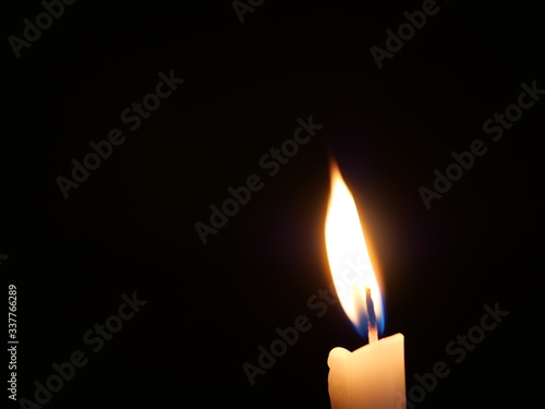 One candle burning alone in the dark.