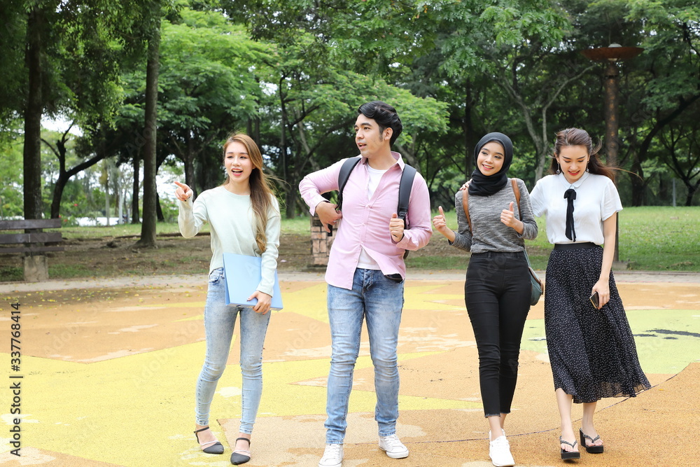 Young asian malay chinese man woman outdoor park walk stand study talk discuss point laptop file book backpack Young asian malay chinese man woman outdoor park walk stand study talk discuss point laptop file book backpack