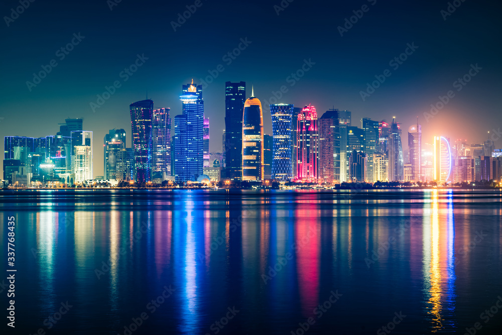 Night view on the centre of the city Doha, Qatar with many modern luxury building and skyscrapers illuminated with bright lights.